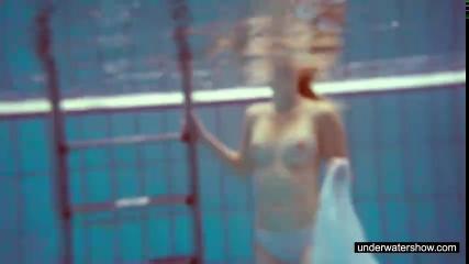 Девушка в бассейне снимает рубашку и показывает свою грудь